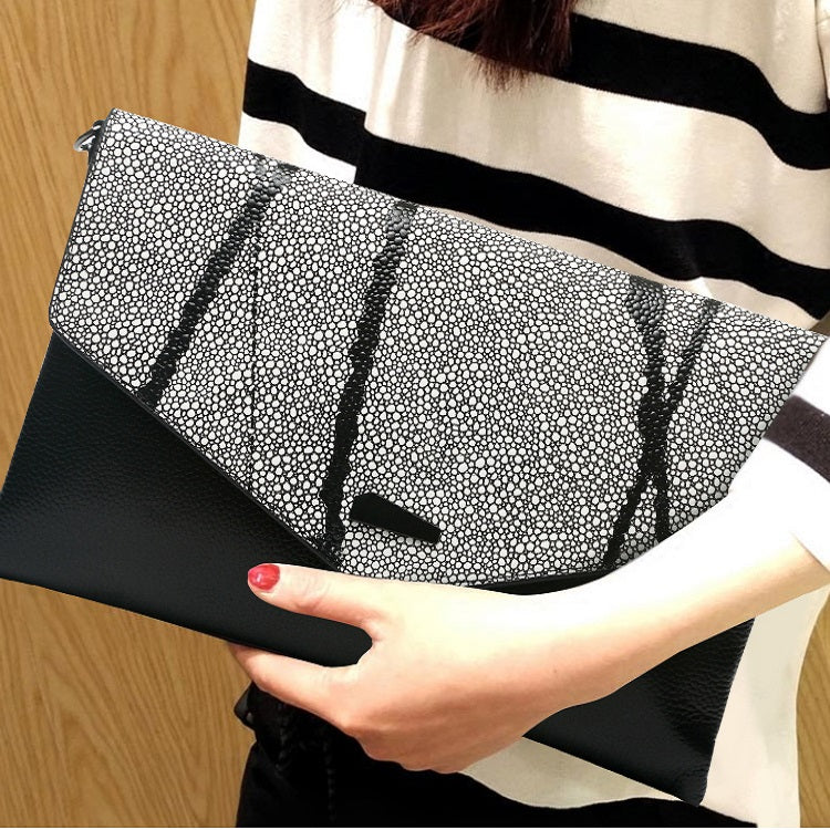 Model holding a gray leather clutch bag