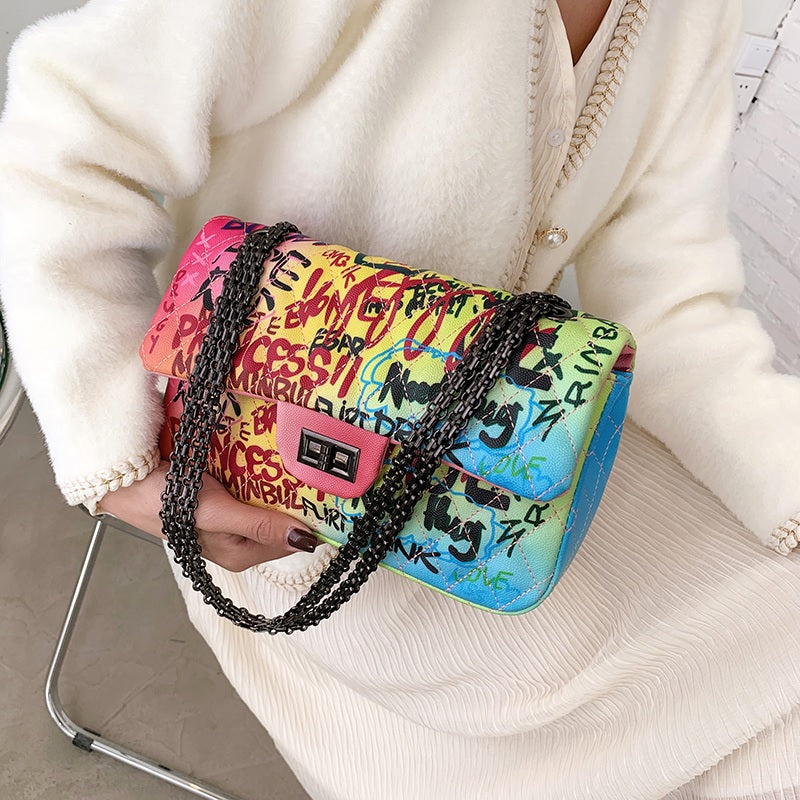 model holding a colorful graffiti clutch bag